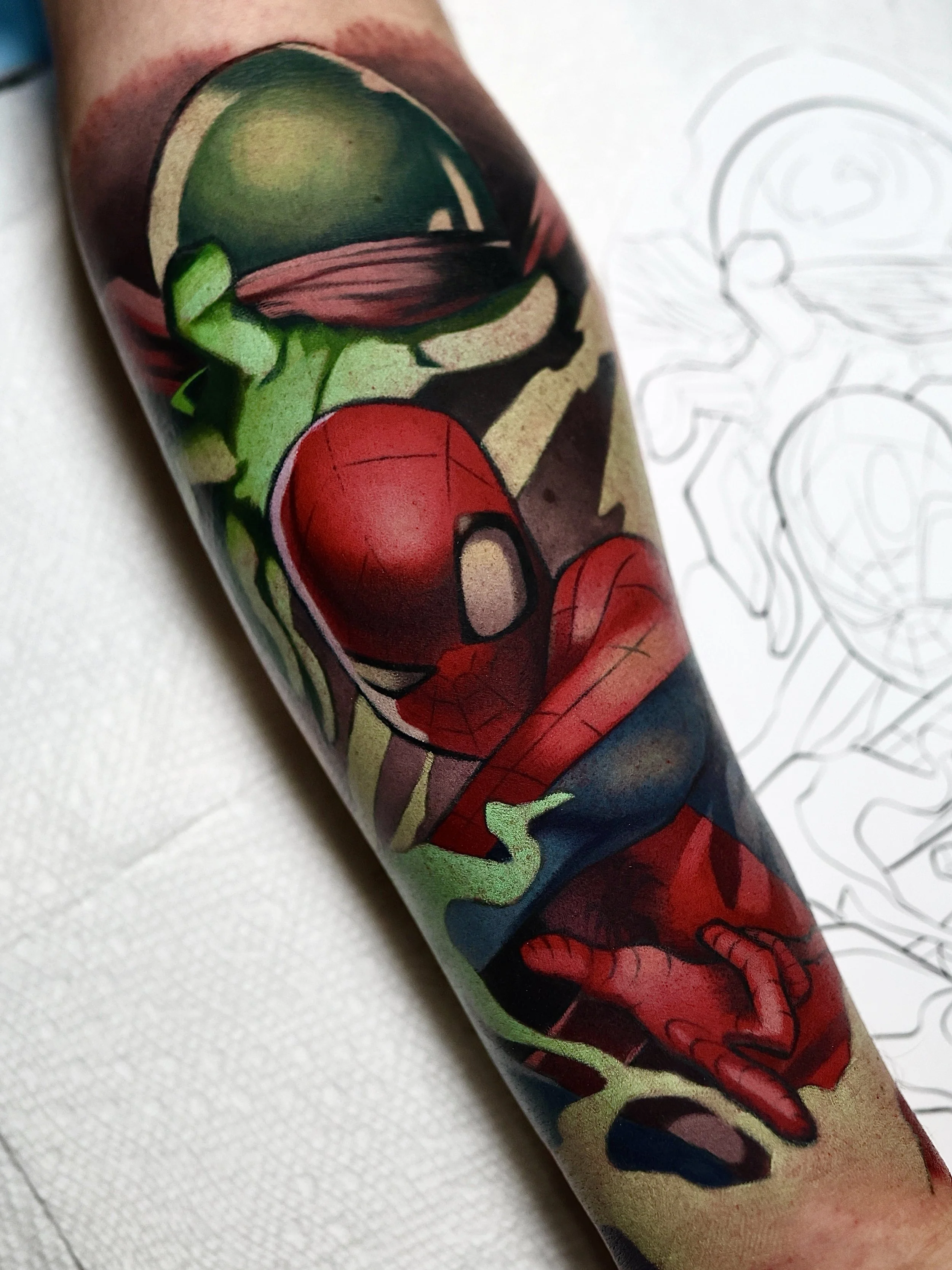 Coloful tattoo of the Character Spiderman in the foreground and Mysterio holding his handout in the backround.
