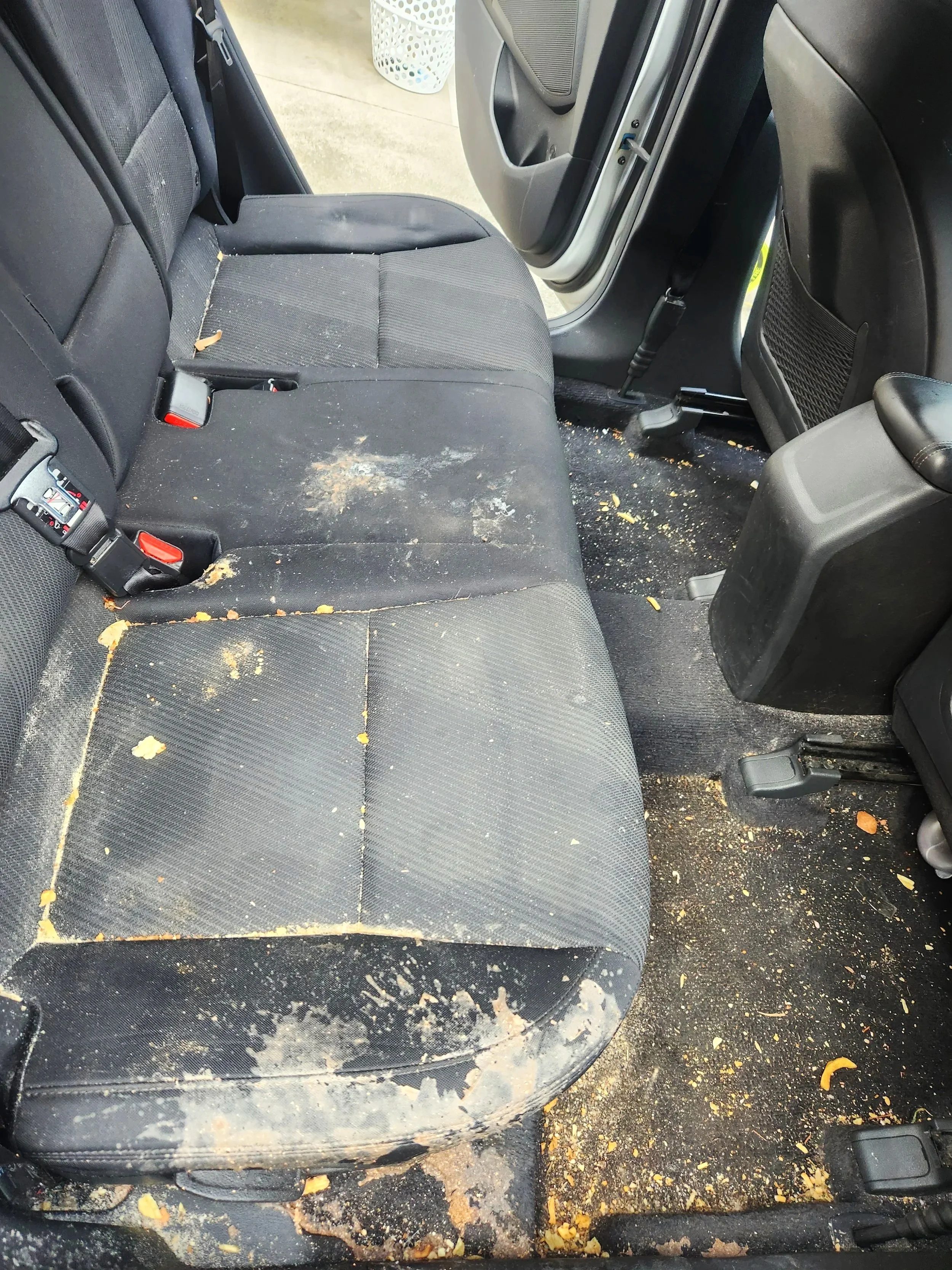 Before: back seat and carpet ahead of a vacuum and full carpet and seat extraction.