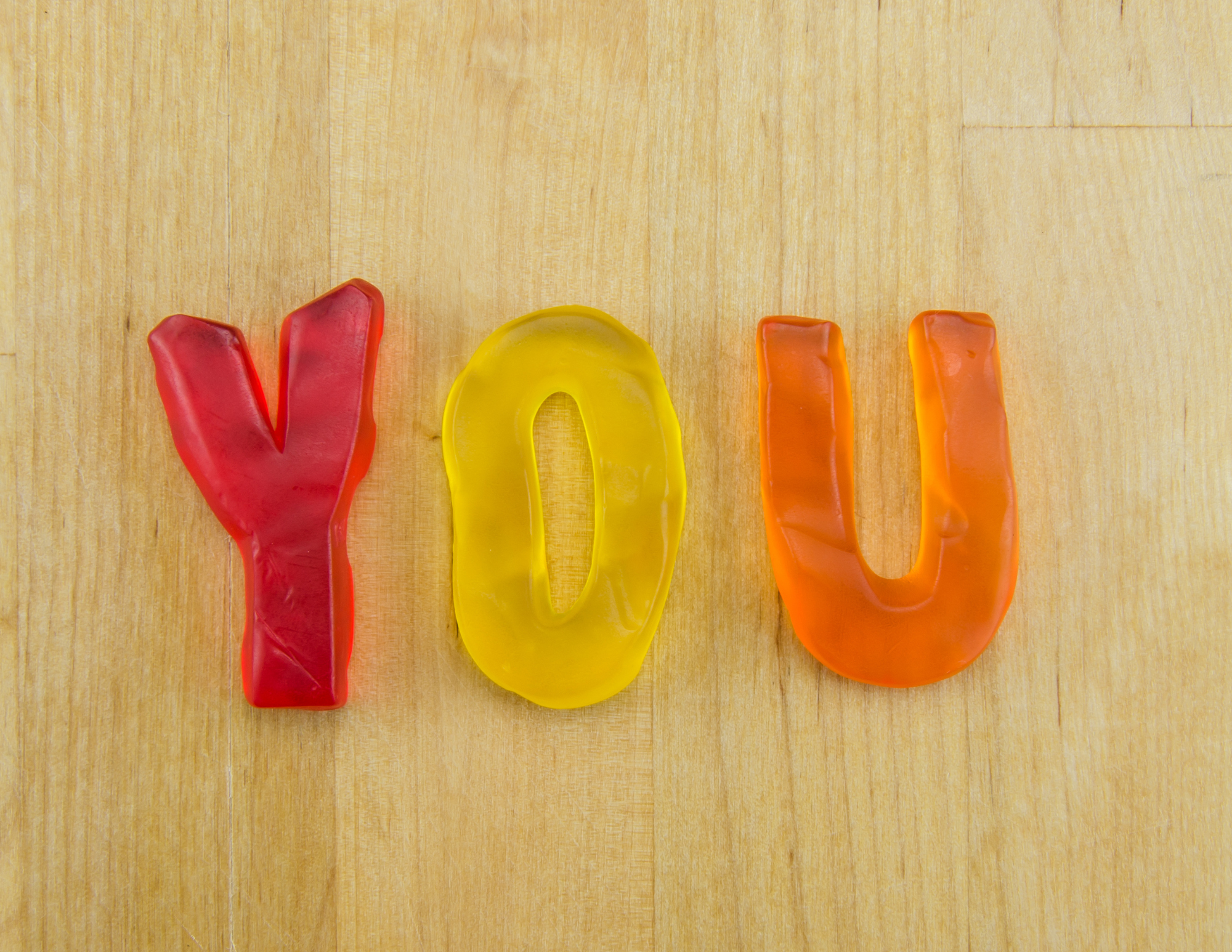 Colorful glass letters spelling 'YOLU' on a wooden surface.