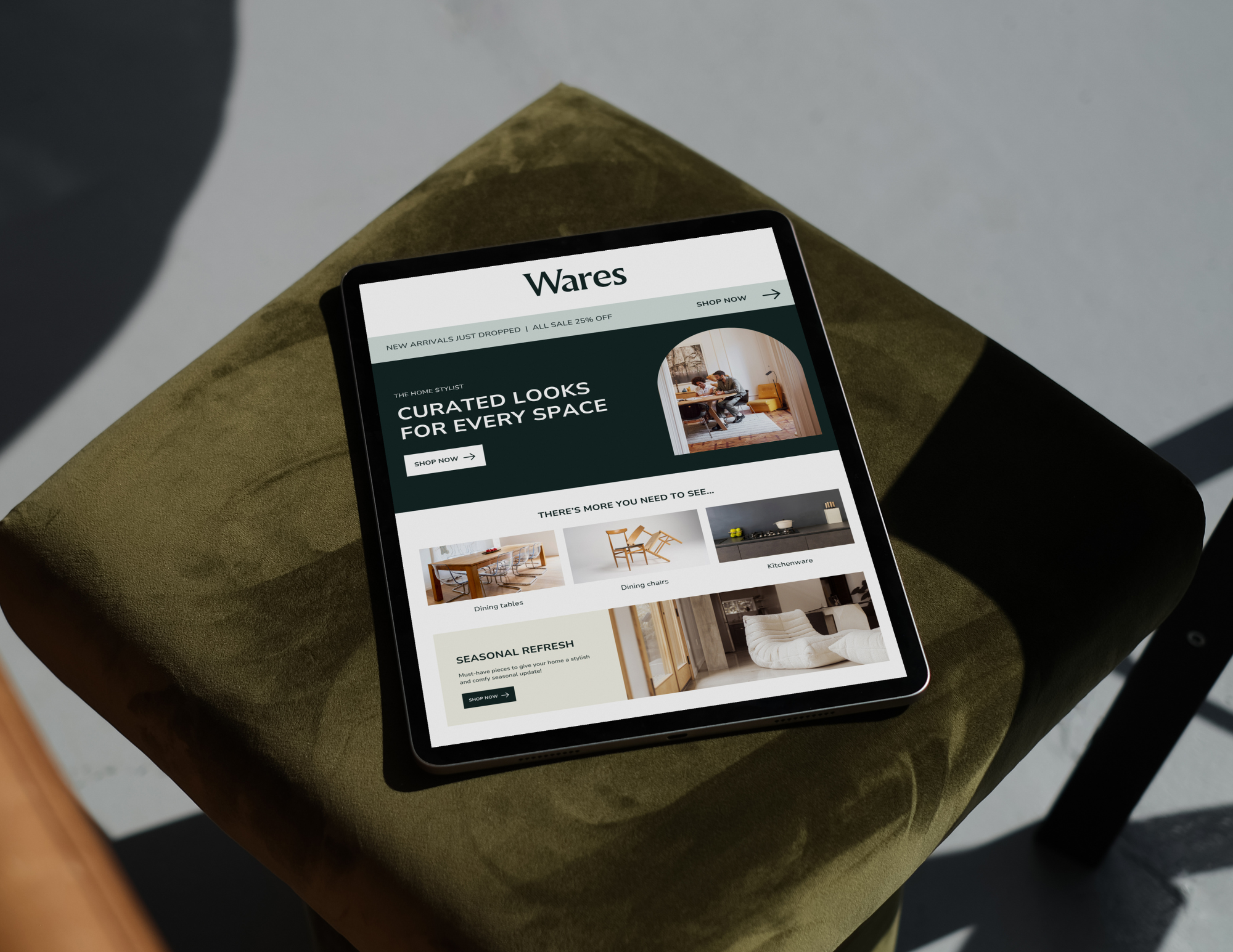 A tablet displaying a furniture website titled 'Wares,' placed on a green fabric ottoman with a gray wall background.