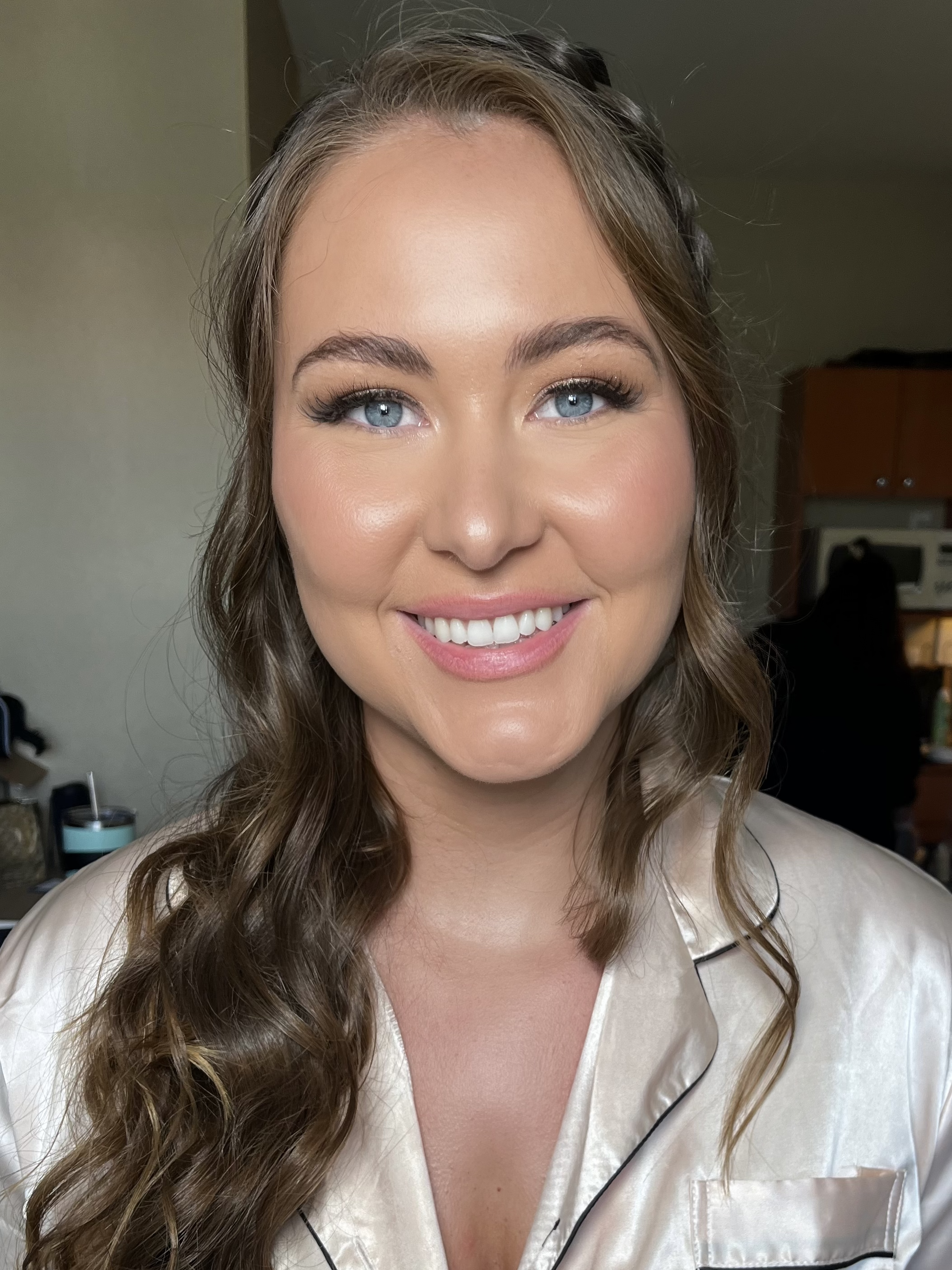 Glowing bridal makeup with softly defined eyes, rosy cheeks and a glossy pink lip.