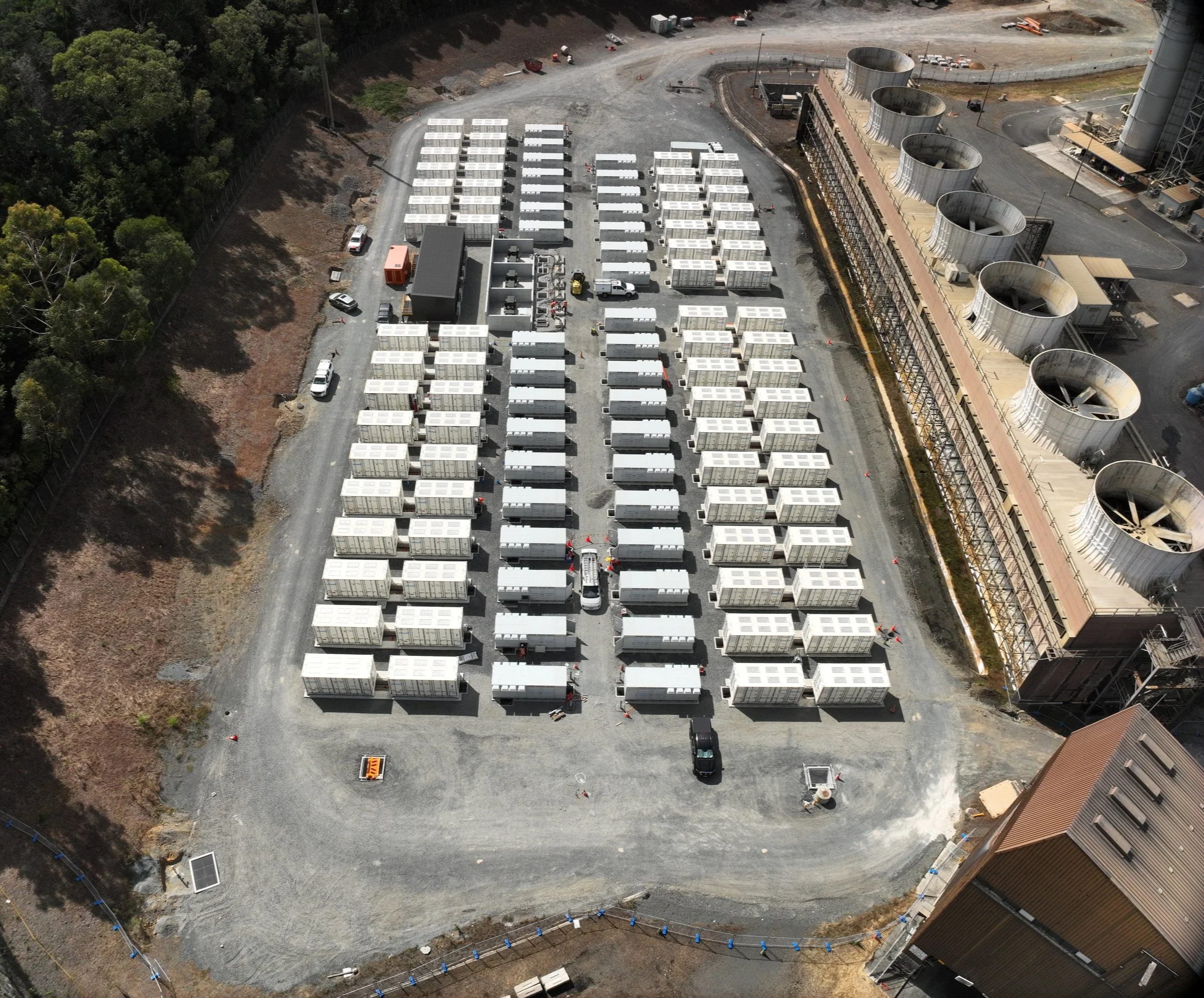 Aerial view of the Huntly Battery Energy Storage System (BESS) under construction, showing rows of battery units and associated electrical infrastructure.