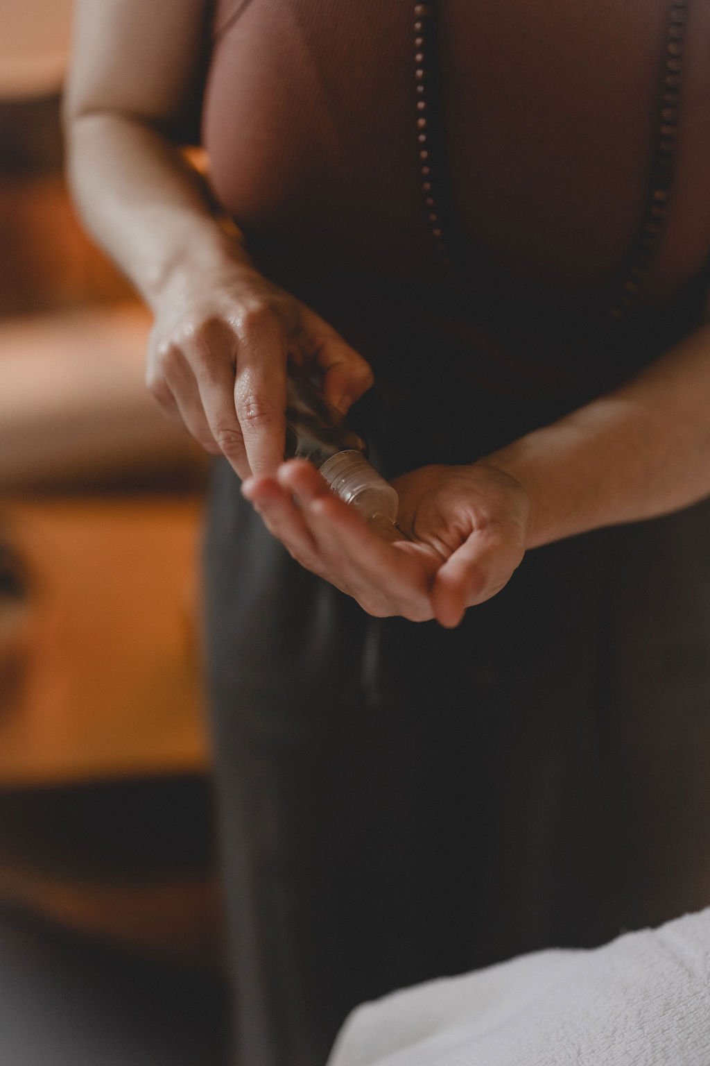 Person filling a small bottle with liquid from a larger container.