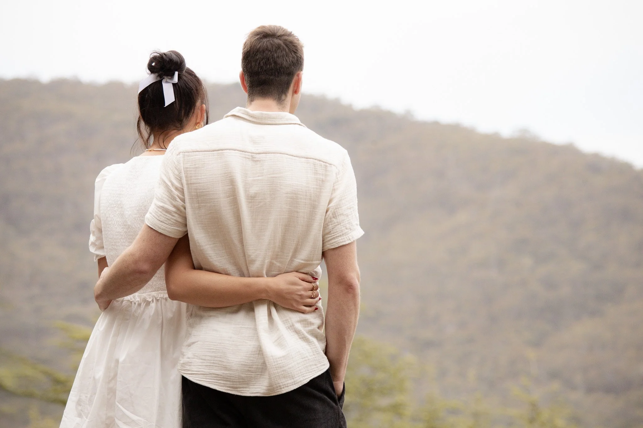 Young couple embracing each other as they overlook black mountain in Canberra