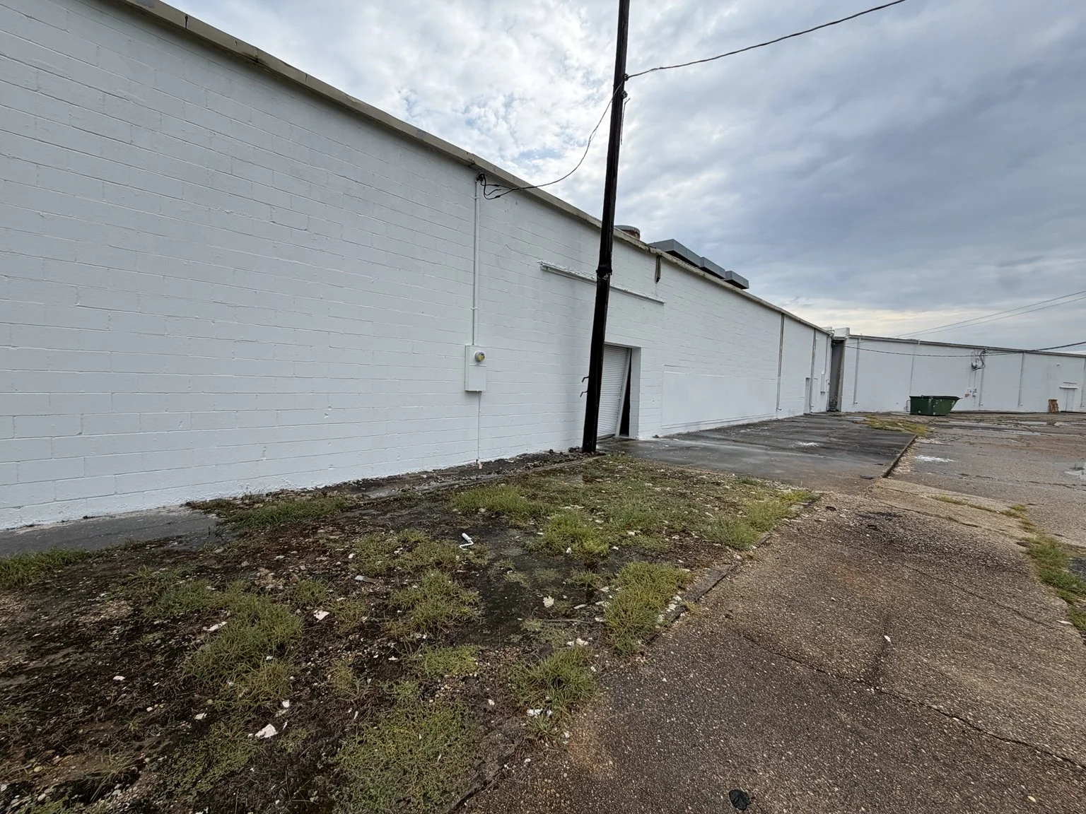Pine Plaza commercial exterior painting — completed long wall in dark gray.