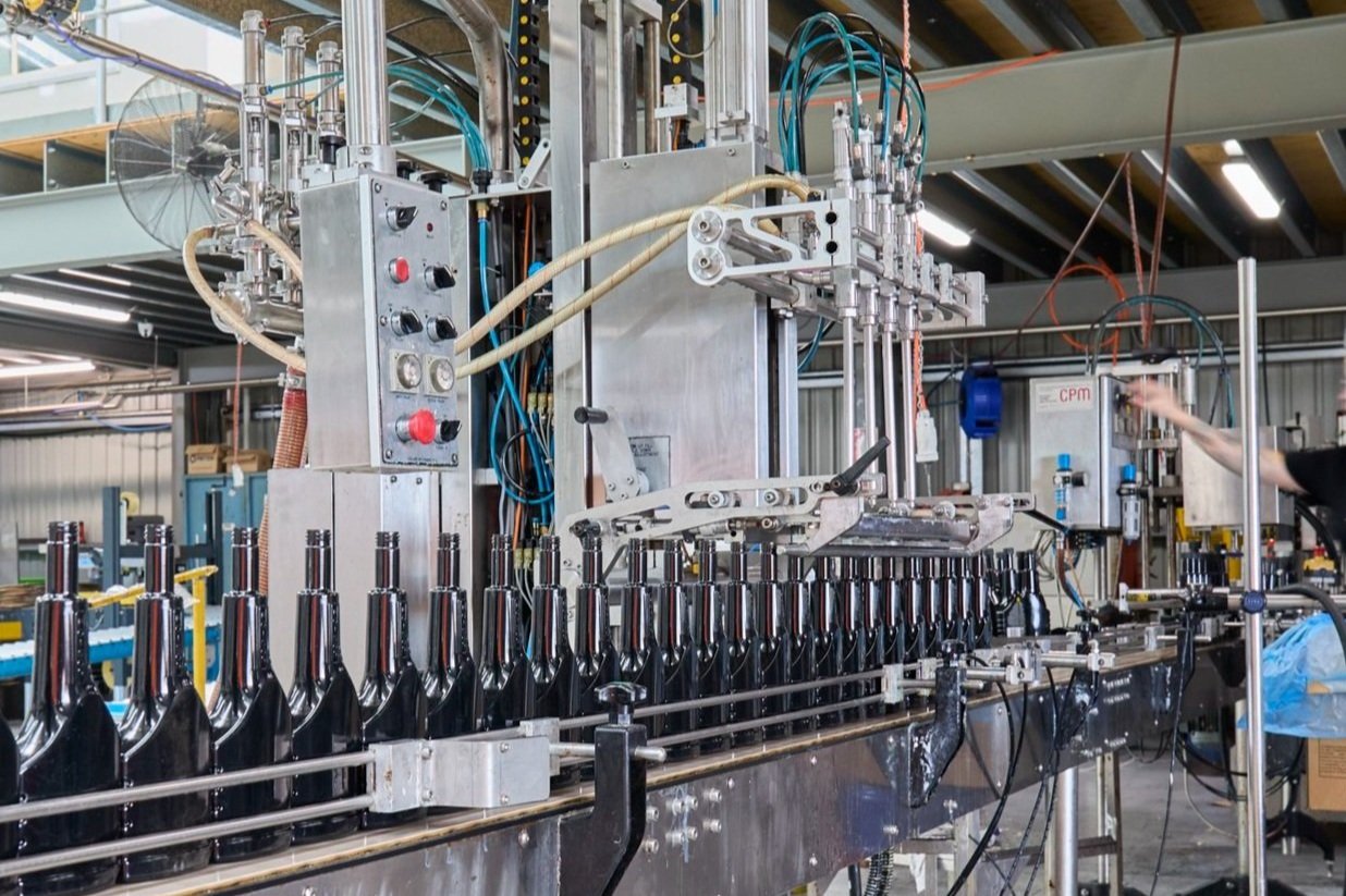 Industrial bottling machine filling glass bottles in a factory.