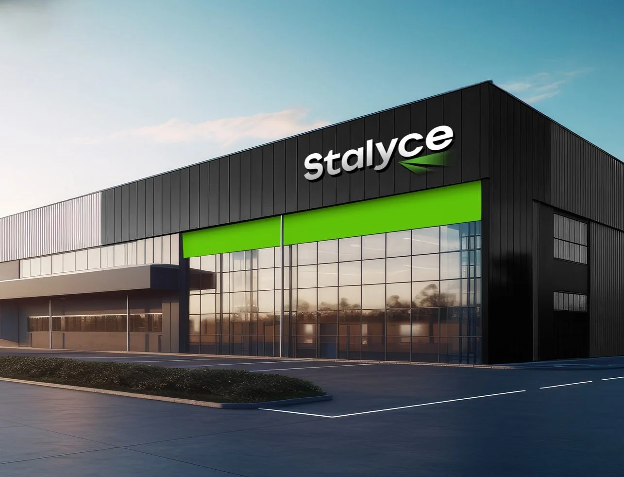 A modern commercial building with black panels, glass windows, and a green feature, with a sign that reads 'stalyce' on the top corner.