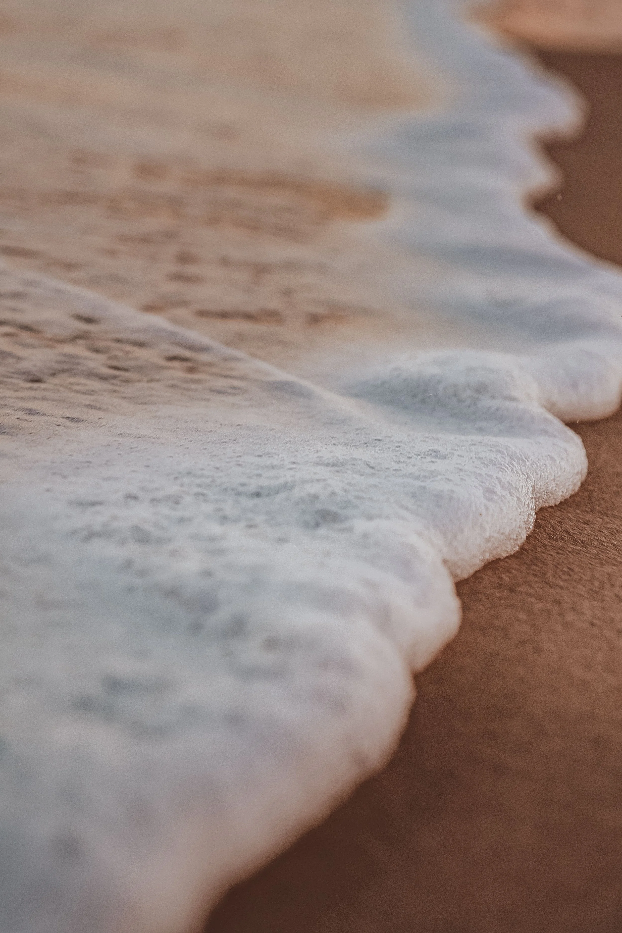 Close-up of ocean waves washing onto a sandy beach.