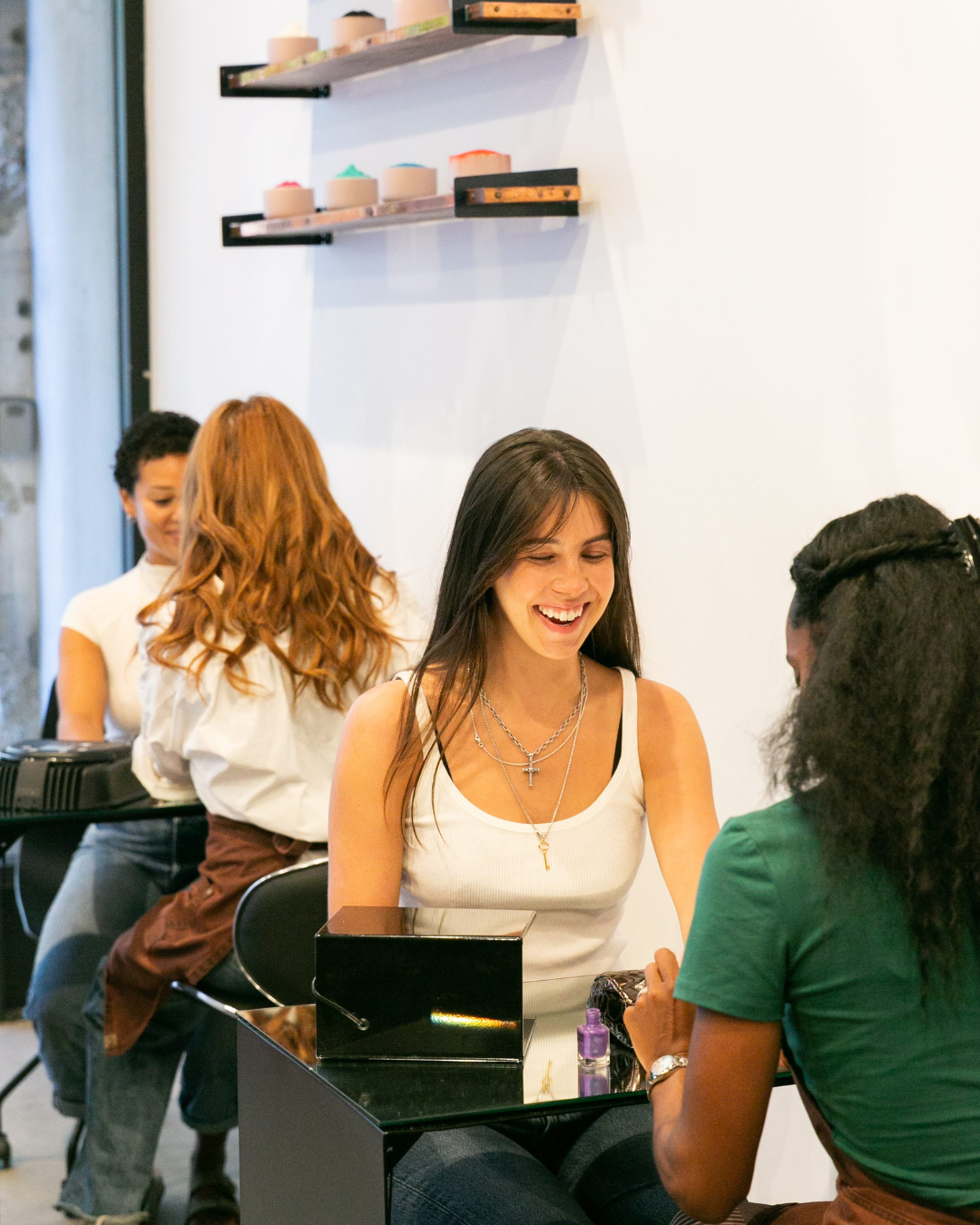 Women having a manicure at a nail salon, smiling and engaging in conversation.