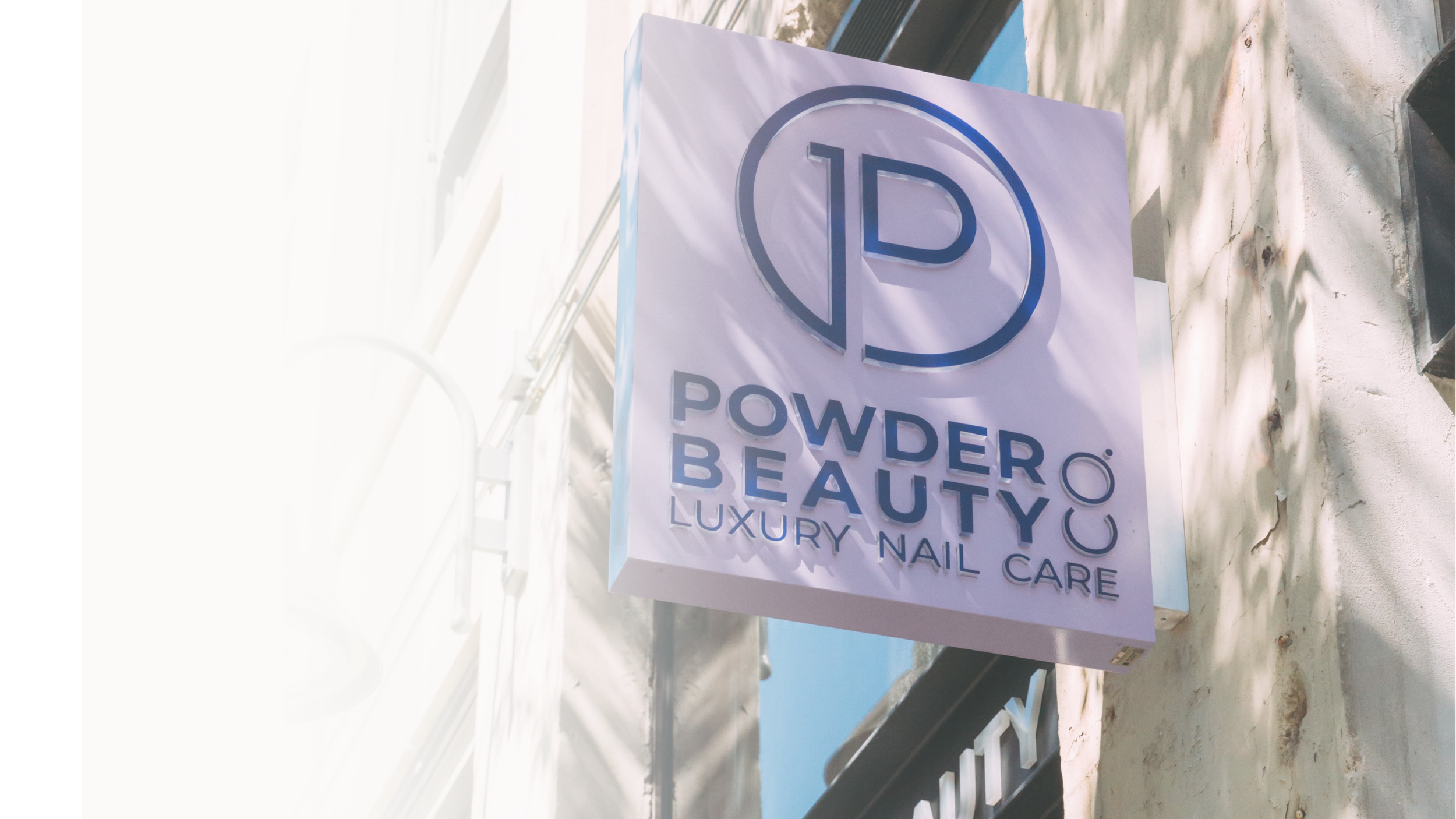 Store sign for Powder Beauty, a luxury nail care business, showing a logo with a circle and a P inside it.