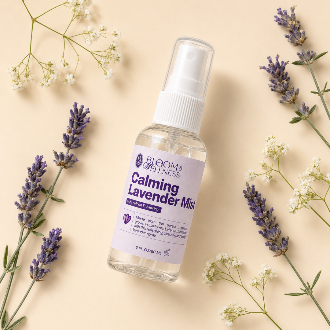 A clear spray bottle labeled 'Calming Lavender Mist' from Bloom & Wellness, surrounded by sprigs of lavender and white flowers on a beige background.