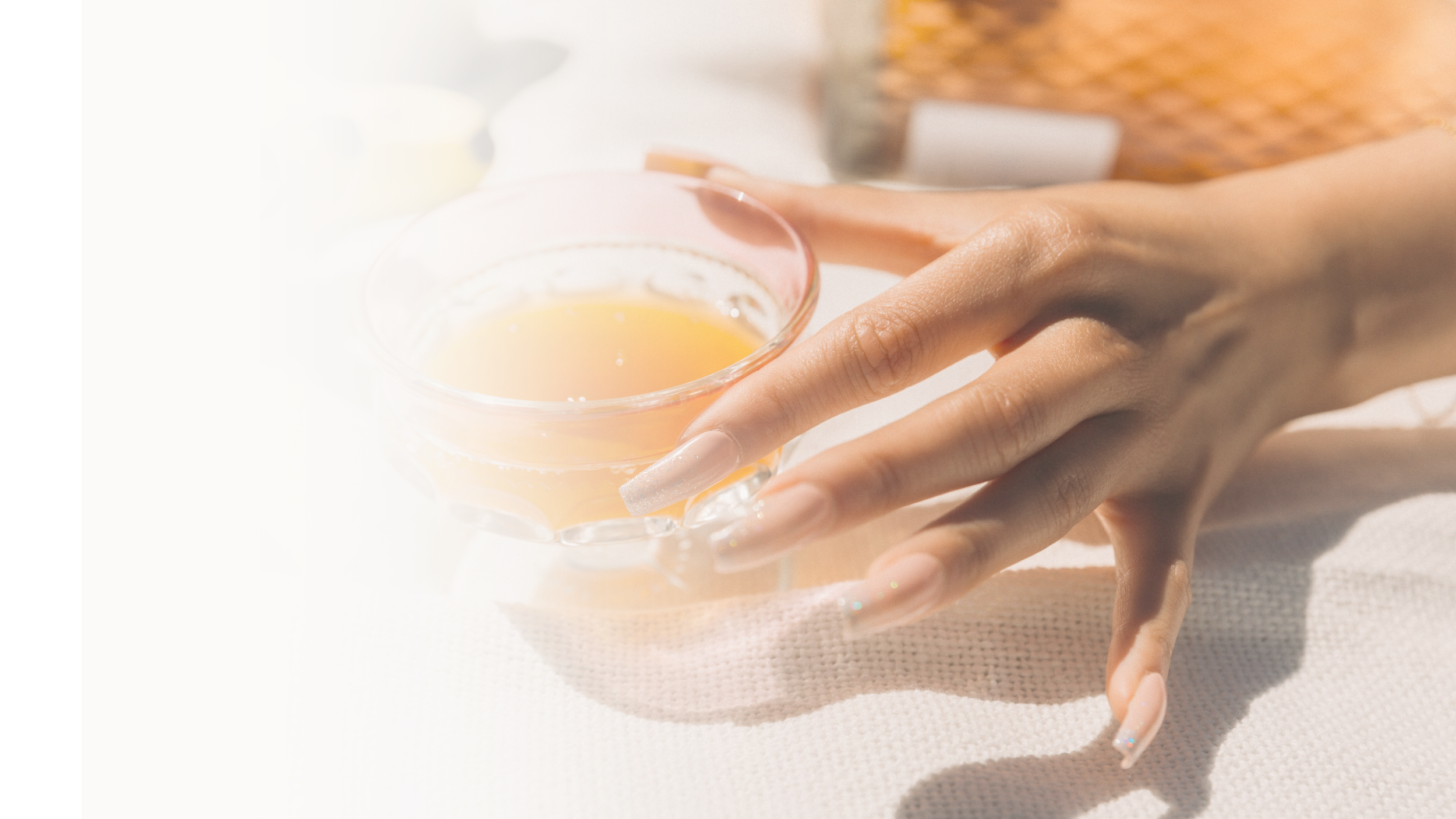 Person holding a glass of orange juice with long manicured nails.
