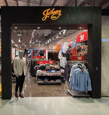 Clothing store entrance with signs indicating discounts, mannequins, and racks of clothes inside.
