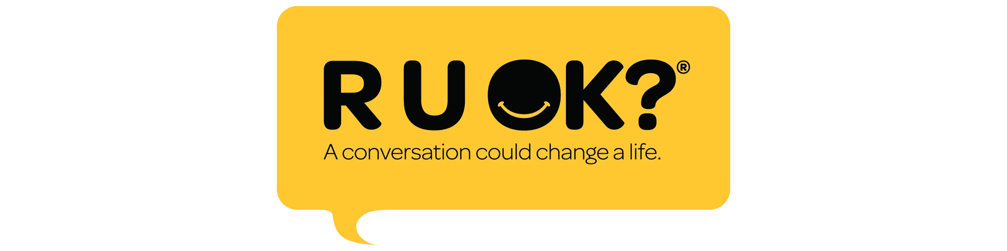 Bright yellow sign with the word "R U OK?" and a smiling face in the letter "O". Below it, the text reads, "A conversation could change a life."