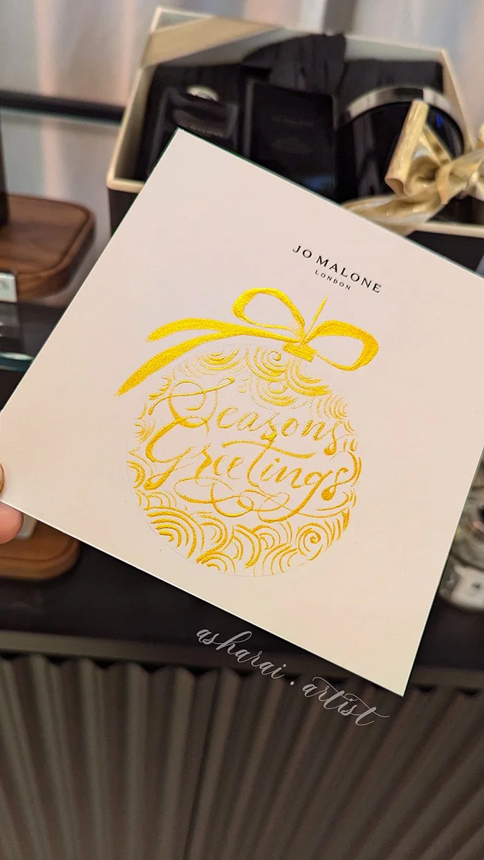 Jo Malone London Noe Card  with gold writing and ornament design that says 'Season's Greetings' ,live in store Calligraphy by AshaRai
