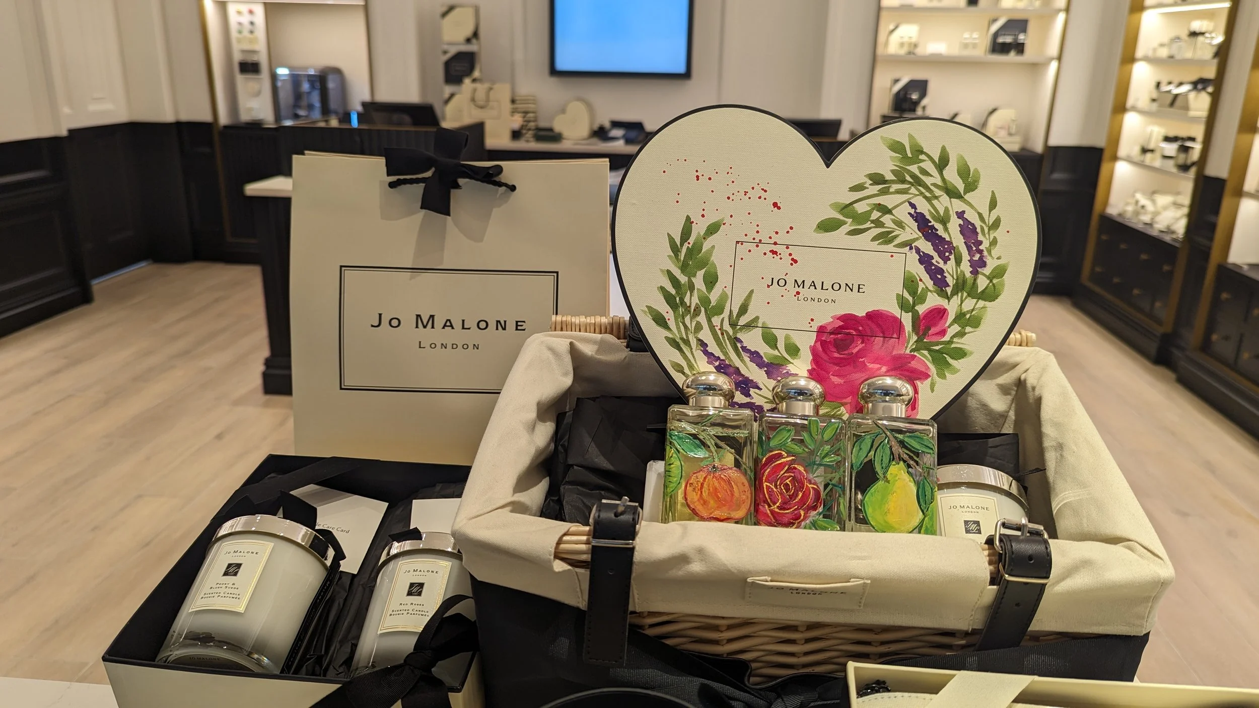 Display of Jo Malone London scented candles and perfume bottles with floral and fruit designs at a retail store.