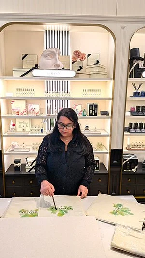 Woman in black shirt demonstrating plant painting in a boutique store.