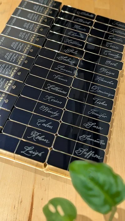 Personalized Clé de Peau Beauté metal lipstick cases, hand engraved with clients’ names for a luxury beauty brand activation. Marketing activation