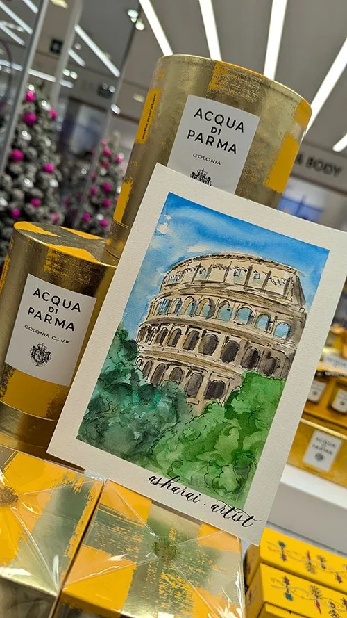 A display of Acqua di Parma cologne bottles with a watercolor postcard of the Colosseum in Rome, Italy. Event at holt Renfrew .Live event artist Toronto