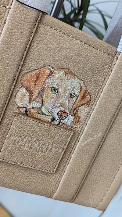 A beige leather item with a painted image of a puppy in a pocket.