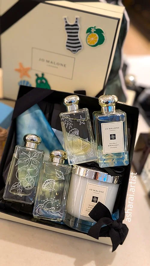 Custom hand engraving at Jo Malone London, Eaton Centre, Toronto, featuring Sea Salt & Bergamot scented candles and glass bottles engraved with delicate seashell designs. Luxury engraving and personalized fragrance gifts.