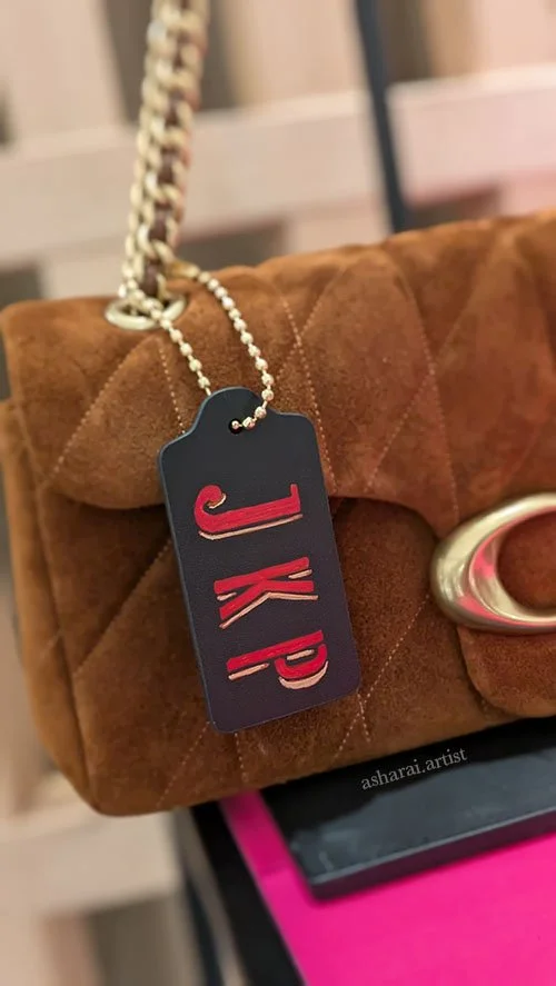 Brown quilted Coach handbag featuring custom hand-painted red initials “J K P,” created live by a leather painter at the Coach event at Holt Renfrew Bloor Street in Toronto.