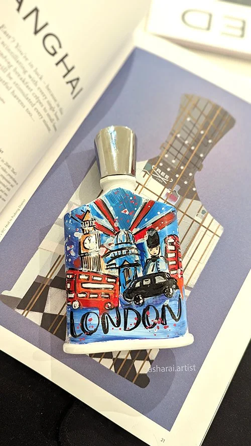 Creed perfume bottle Painted with London landmarks, a double-decker bus, red telephone booth, and a black cab, with a Union Jack flag background. Private perfume event