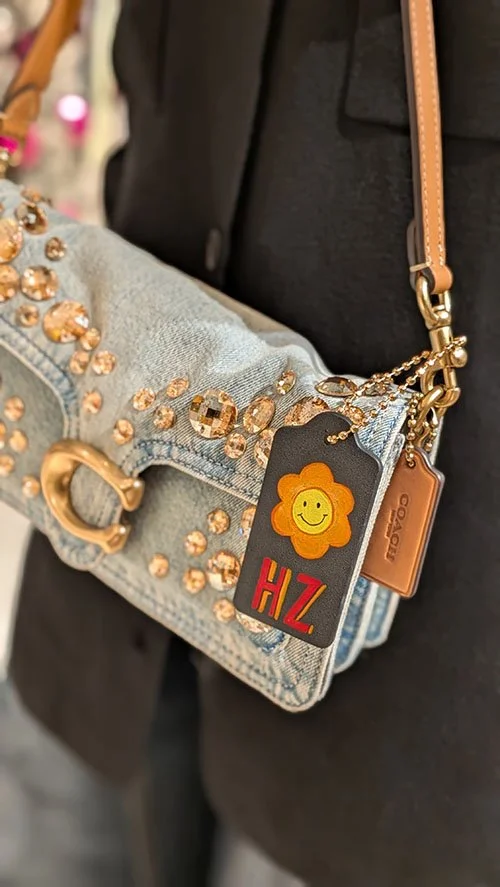 Coach Denim handbag with custom painted  tag with a smiley face flower and initials by live events artist.