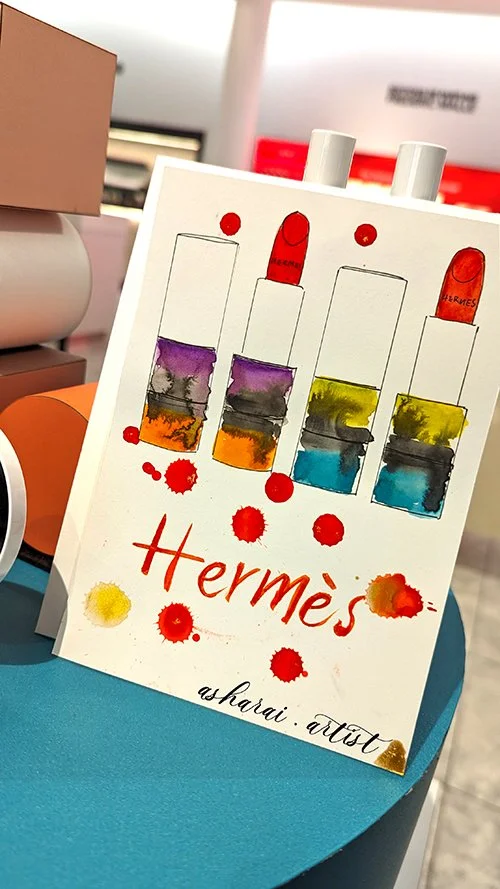 Live watercolor painting by AshaRai for the Hermès new lipstick launch at Holt Renfrew Yorkdale, showcasing luxury event artistry.