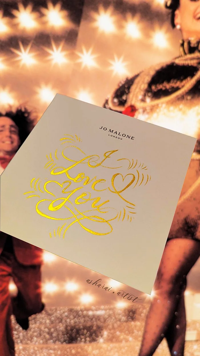 A Jo Malone Note card with gold foil lettering that says 'I Love You' with hearts and decorative lines.