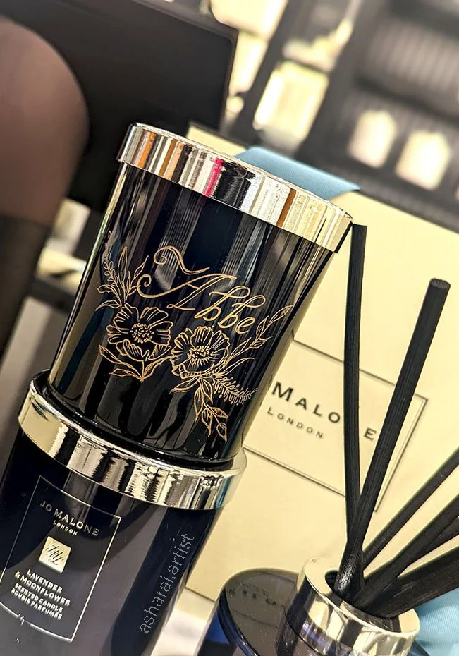 Jo Malone London scented candle with black and gold floral design, surrounded by reed diffusers and gift boxes.