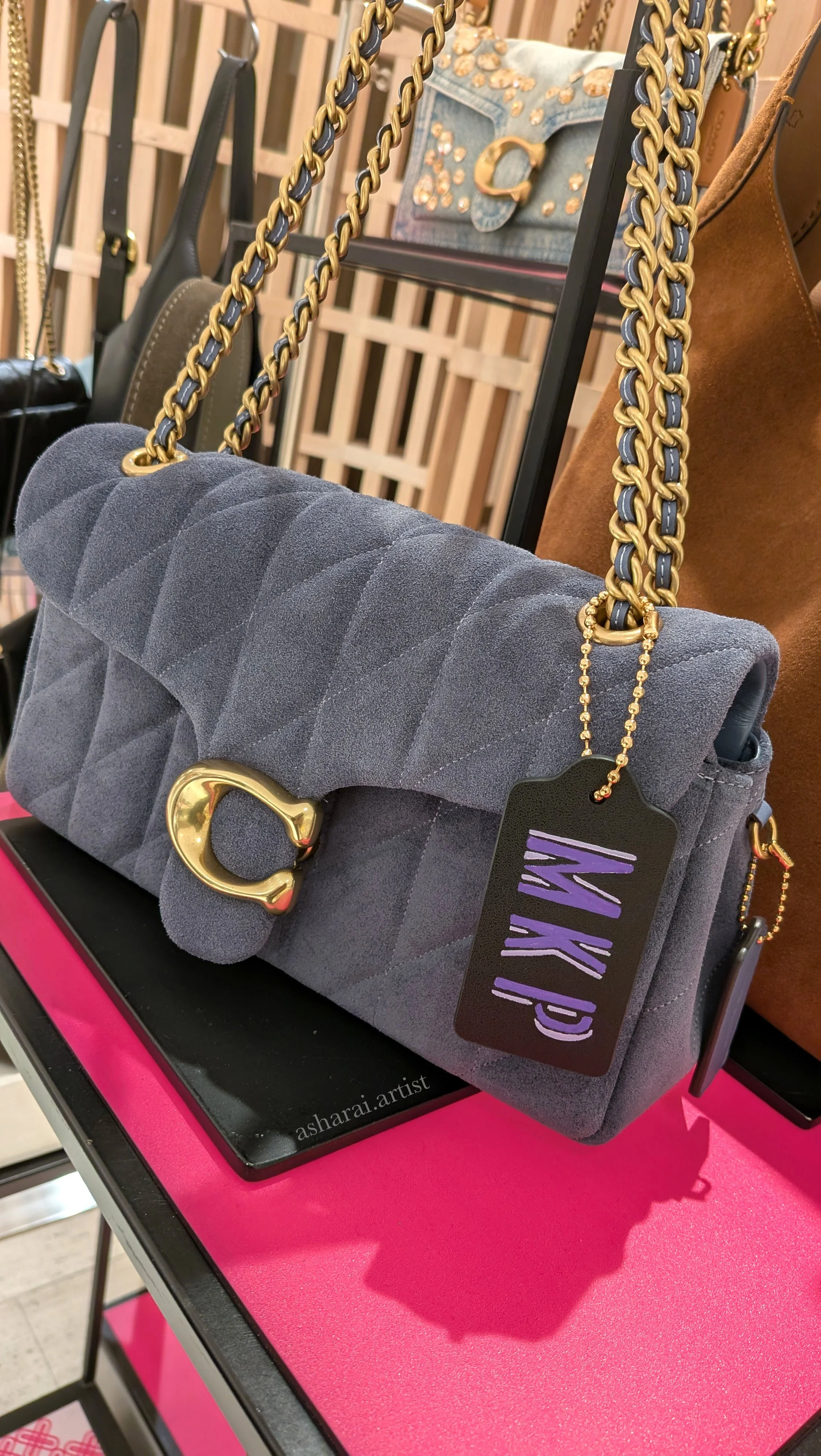 Gray quilted Coach handbag featuring custom hand-painted purple initials “M K P,” created live by a leather painter at the Coach event at Holt Renfrew Bloor Street in Toronto.