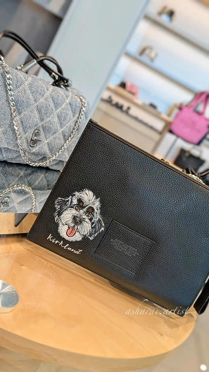 Marc Jacobs leather pouch featuring a custom hand-painted pet portrait by AshaRai, luxury event artist, during a live in-store pet portrait event at Yorkdale.