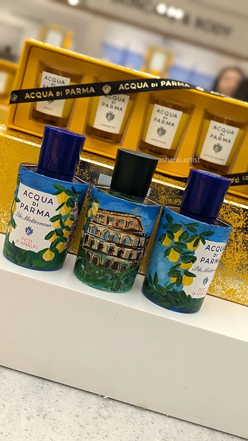 Acqua di Parma perfume bottles featuring hand-painted lemons and the Colosseum, showcasing live bottle painting by a luxury event artist at Holt Renfrew Bloor Street.