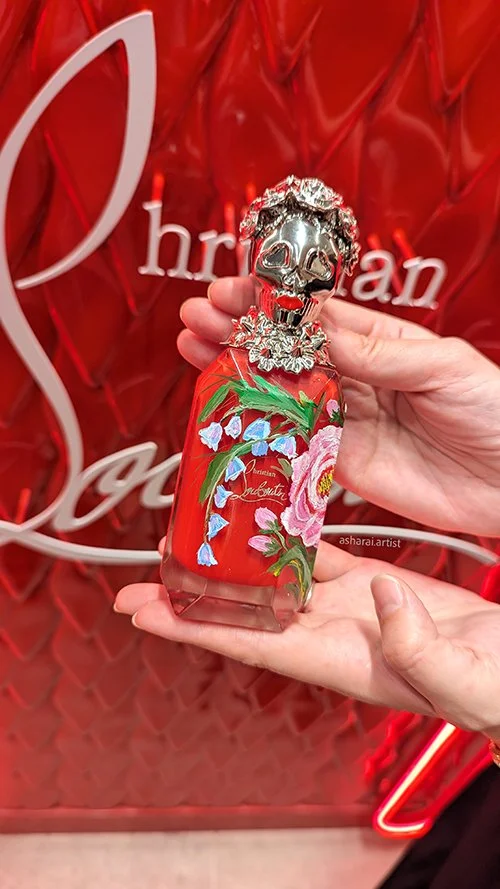 Christian Louboutin's  Loubikiss Eau de Parfum bottle hand-painted with roses and bluebells by a luxury event artist at Holt Renfrew, Bloor Street and Yorkdale location, Toronto.