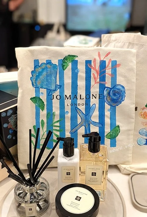 Jo Malone canvas tote bags featuring hand-painted seashells and Italian coastal-inspired designs, showcasing custom live painting for luxury brand events.