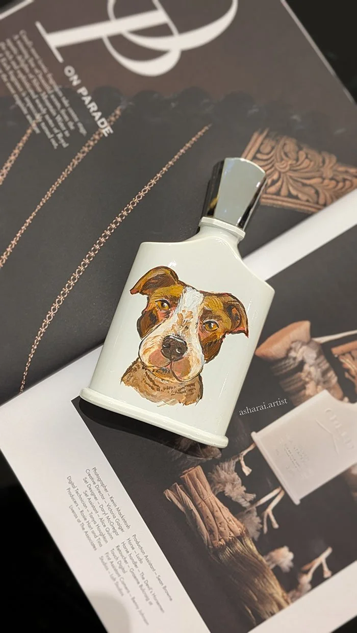 Creed perfume bottle featuring a hand-painted custom pet portrait by AshaRai, luxury event artist, showcasing personalized live bottle painting.