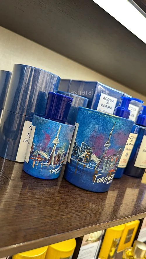 Acqua di Parma perfume bottle and candle featuring a hand-painted Toronto skyline design, showcasing custom live bottle painting by an event artist at Holt Renfrew