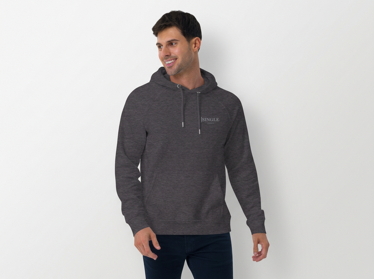 A man wearing a dark gray hoodie with the word 'Single' on it, smiling, standing against a white wall.