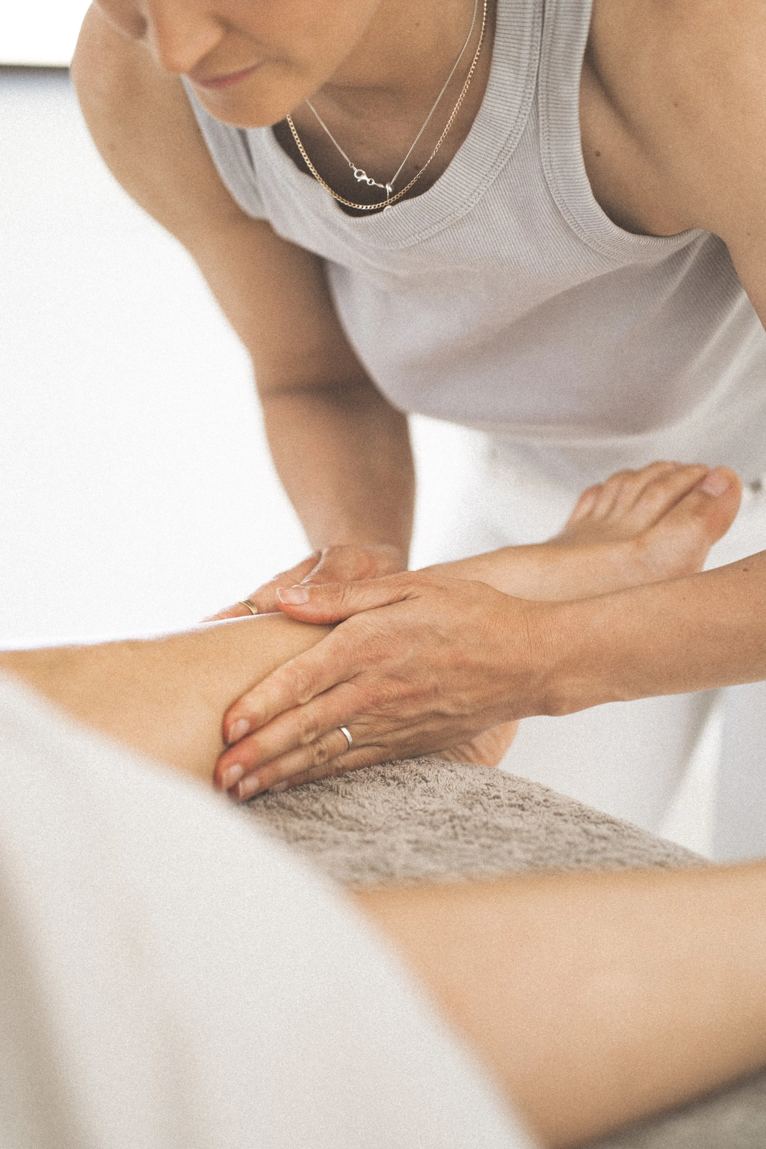 Person performing a massage or physical therapy on a client's leg.