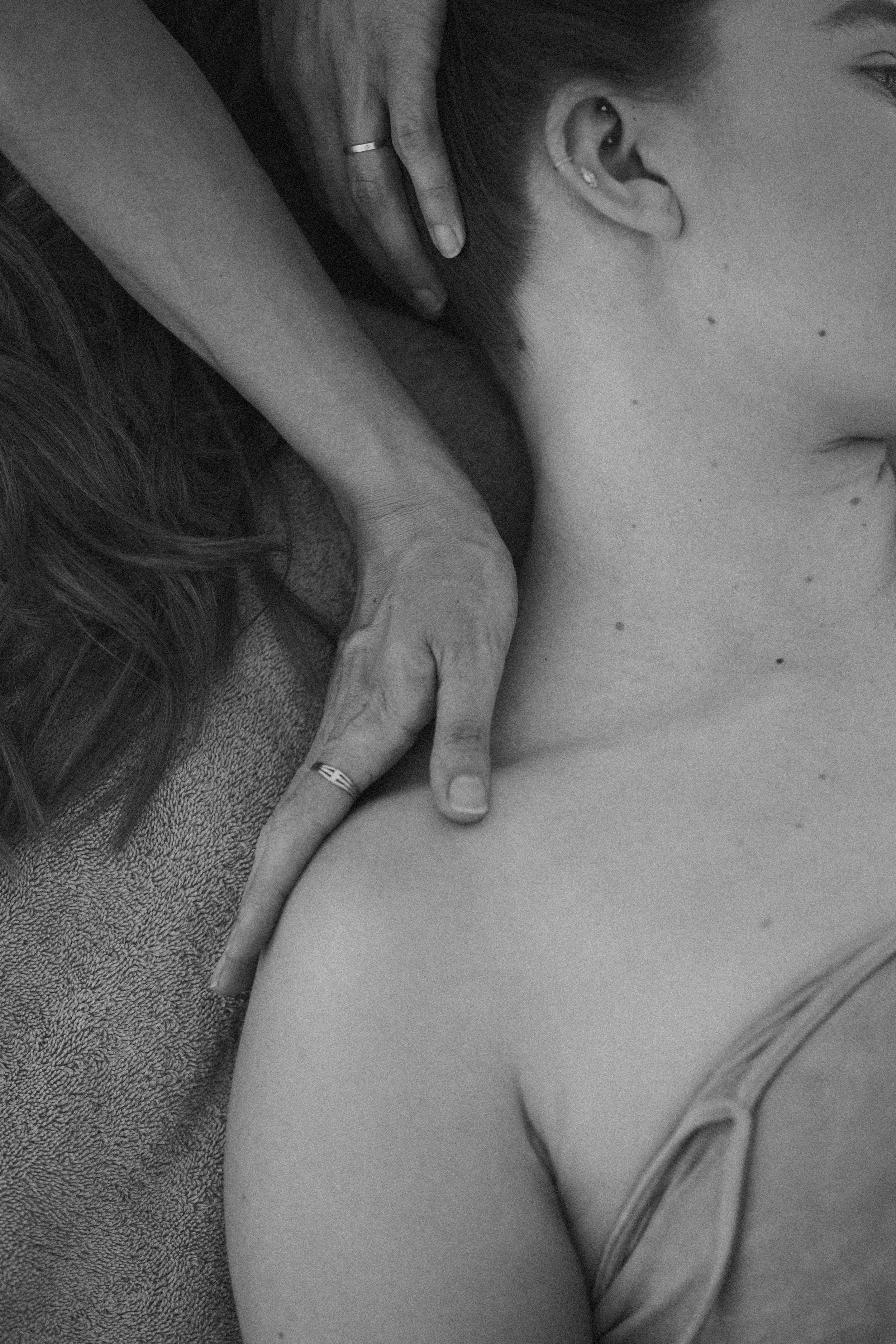 Close-up of a woman receiving a massage, focusing on her shoulder and neck area, with a hand gently applying massage pressure.