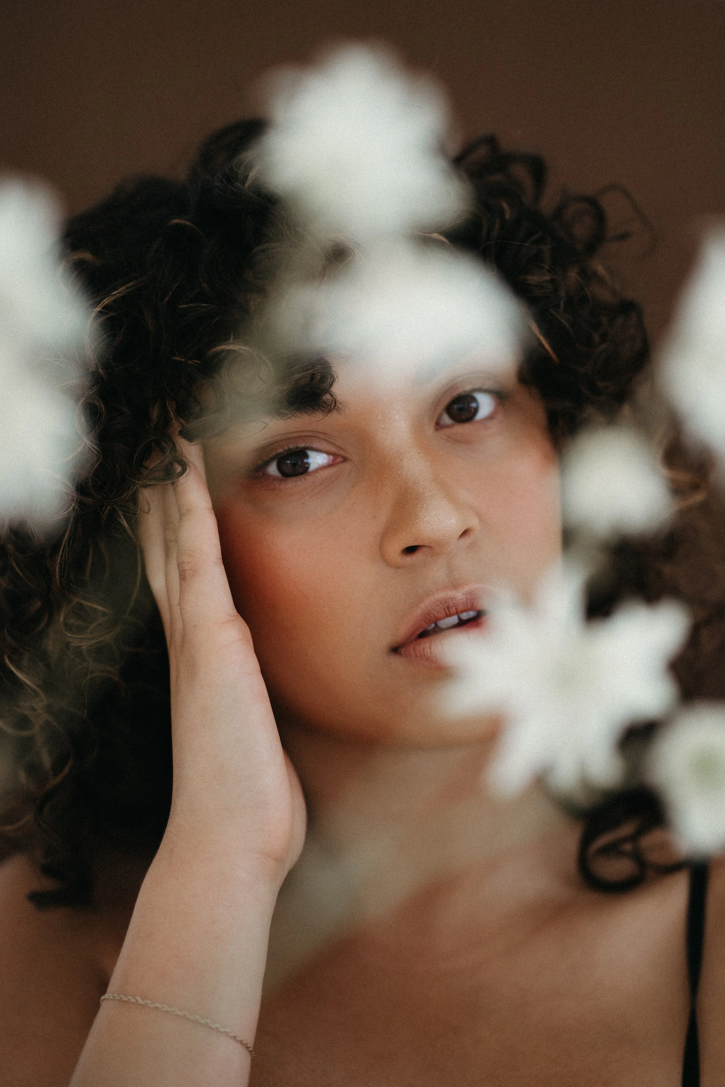 Woman with curly hair surrounded by florals
