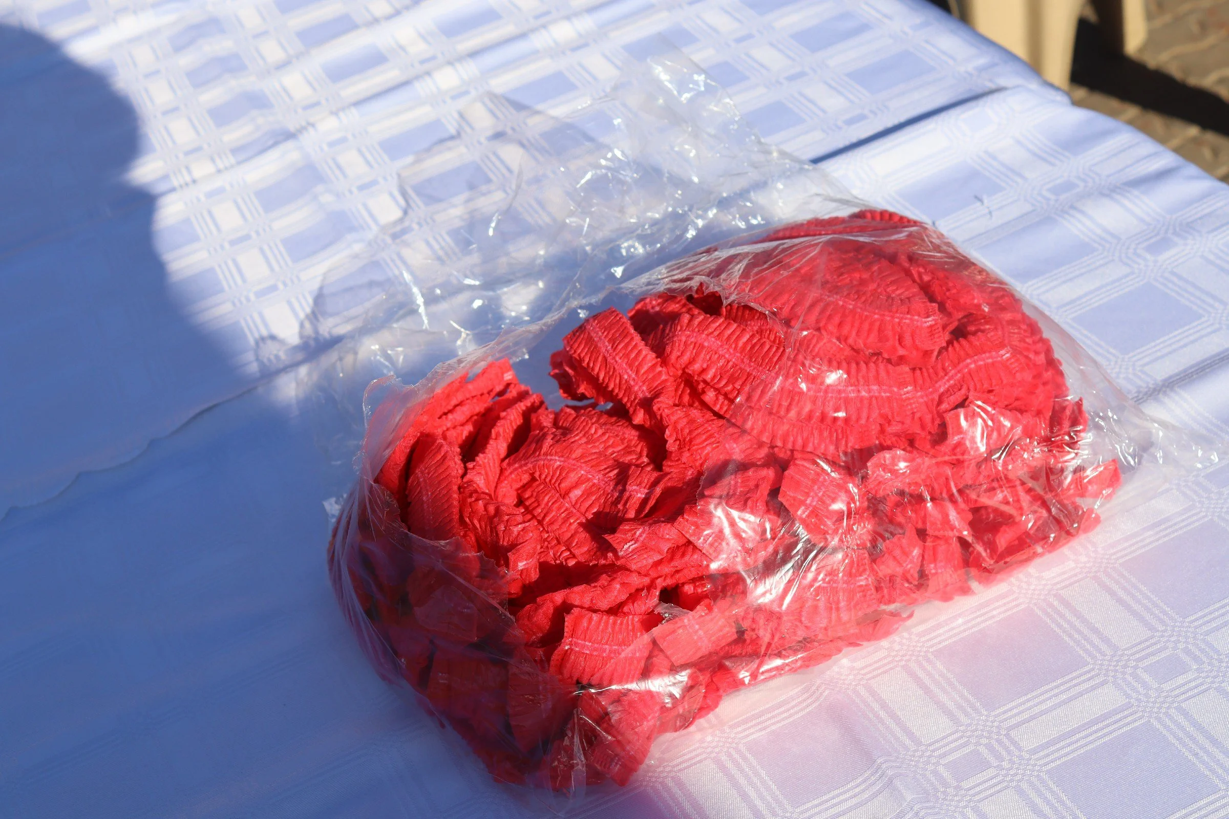 Red crushed candy in a plastic bag on a white table with a blue checkered pattern.