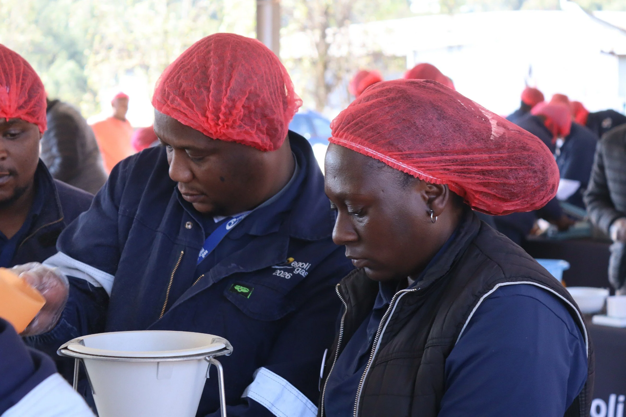 People wearing red hairnets working together at an outdoor event.