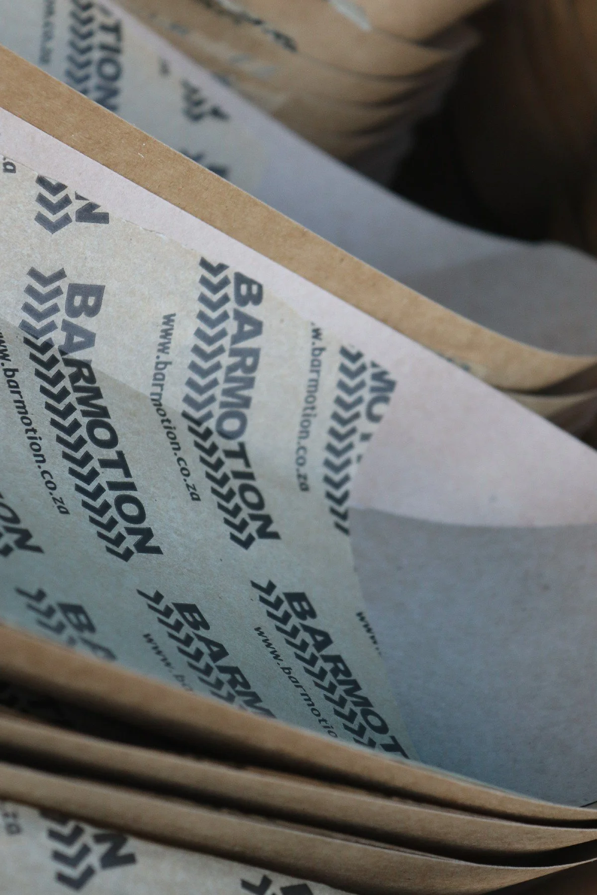 Close-up of paper with the logo 'Barkow' repeated in black with chevron arrows, inside a cardboard box.