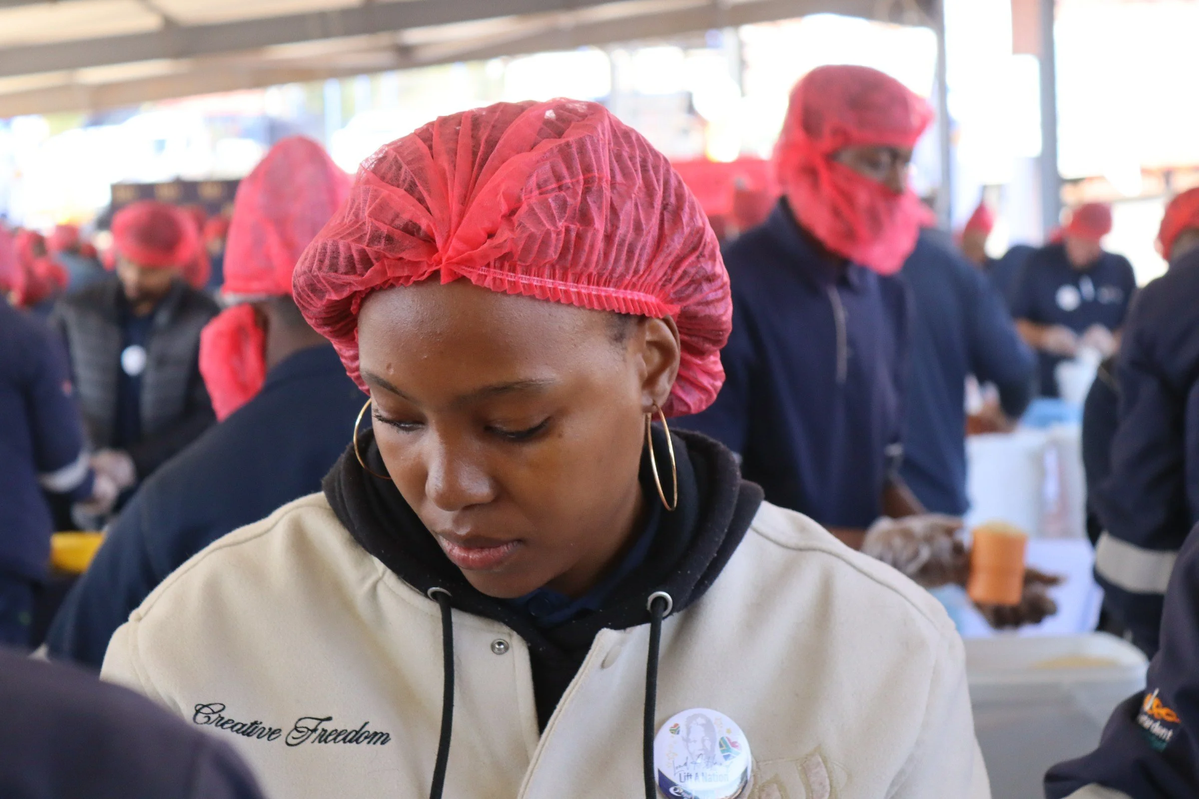 A group of people wearing pink hair covers and dark clothing, participating in a community event or service project.