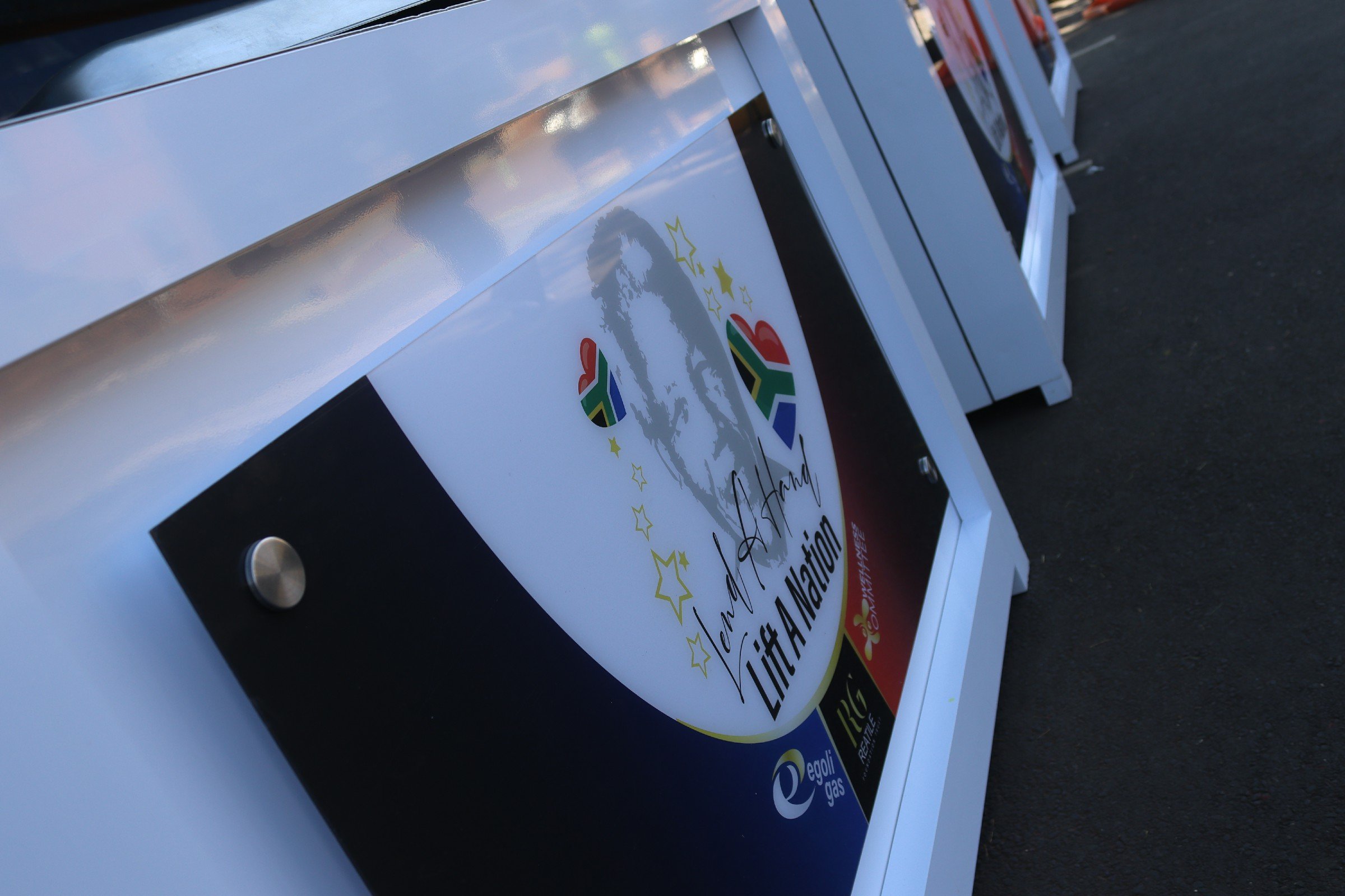 Close-up of a white vehicle with a banner attached, mentioning a campaign for a national election and sponsors like Egoli Gas.
