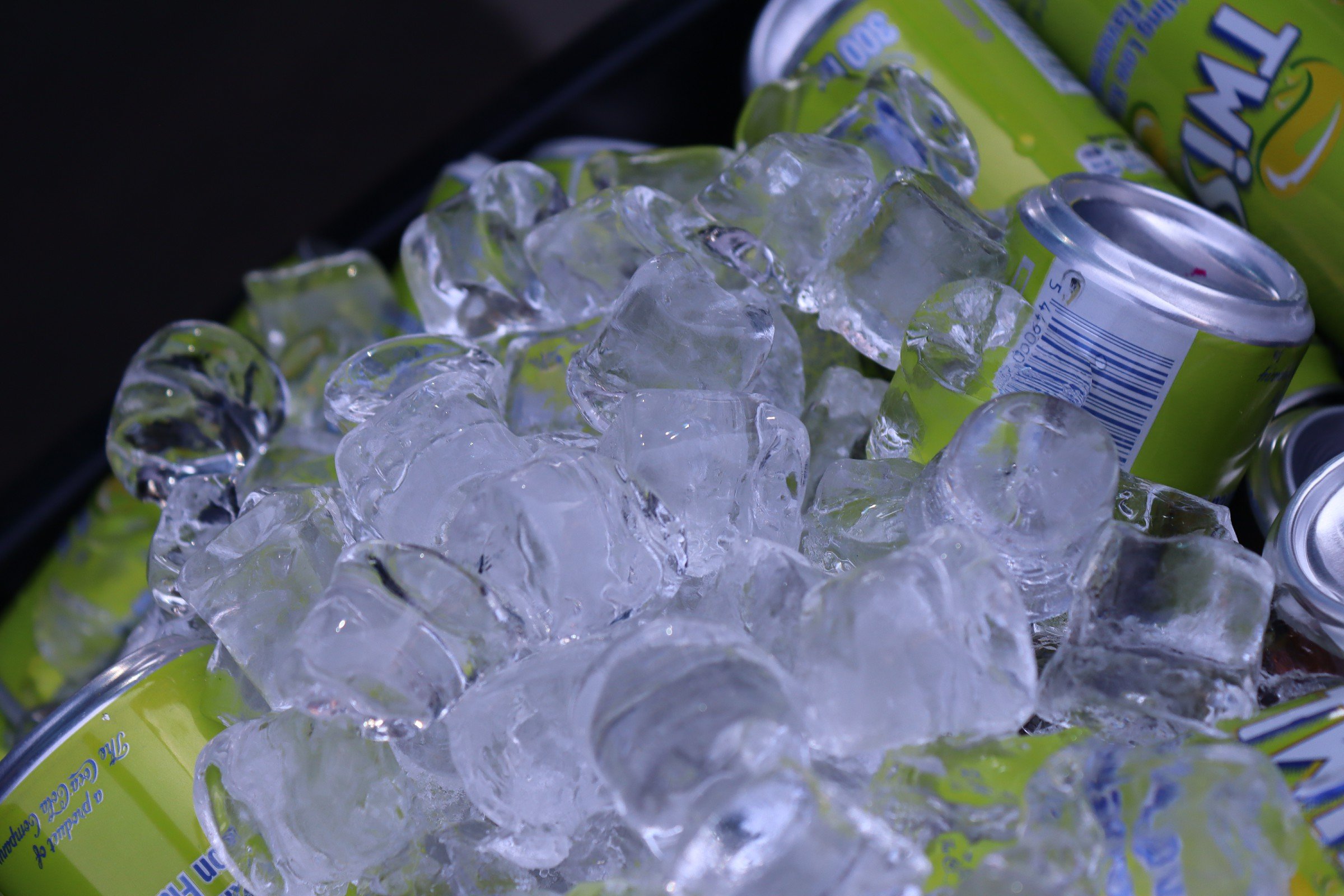 Cans of sparkling water with ice cubes in a cooler.