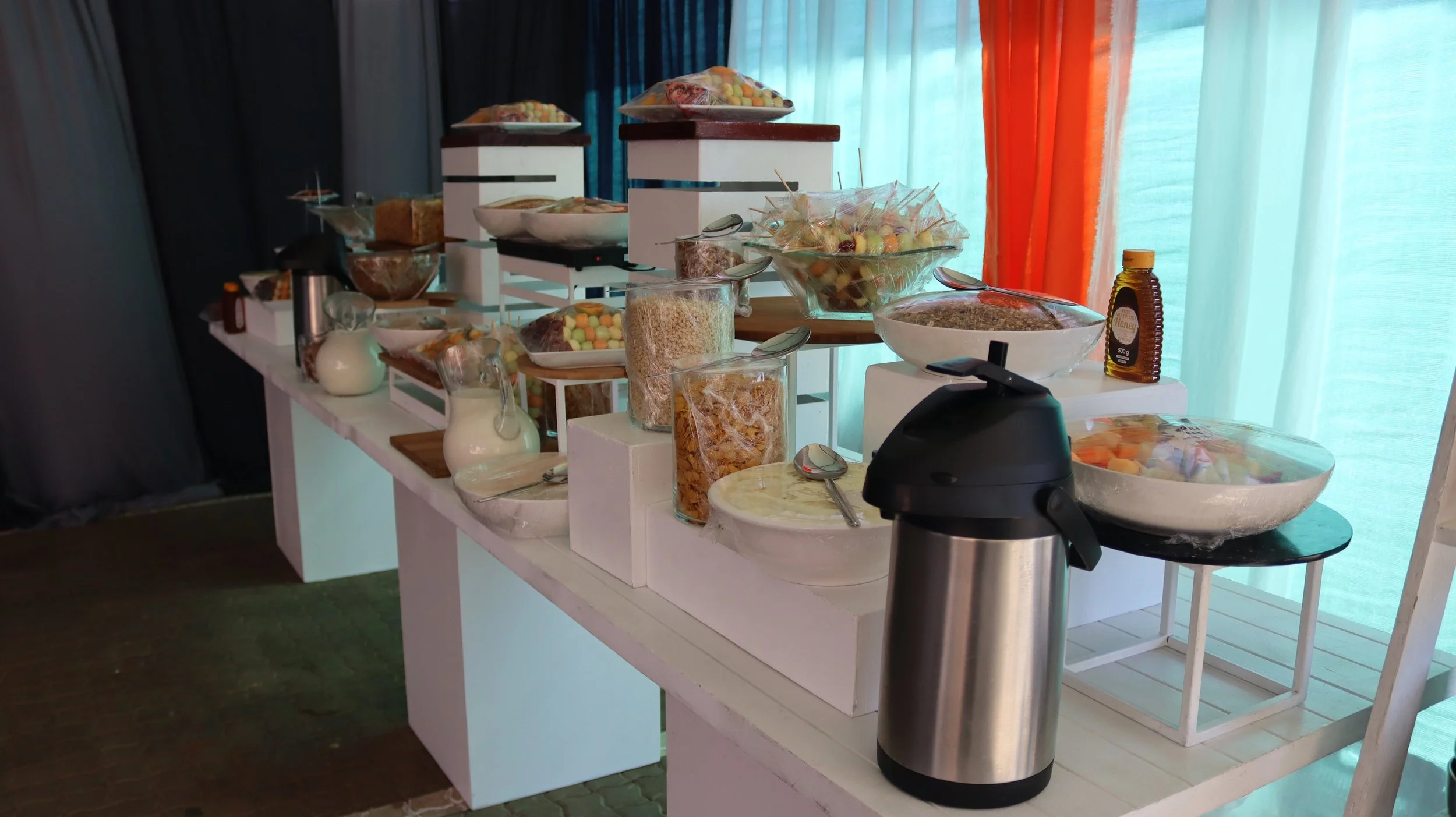 Display of assorted candies and snacks on a white table with a blue and orange curtain in the background.