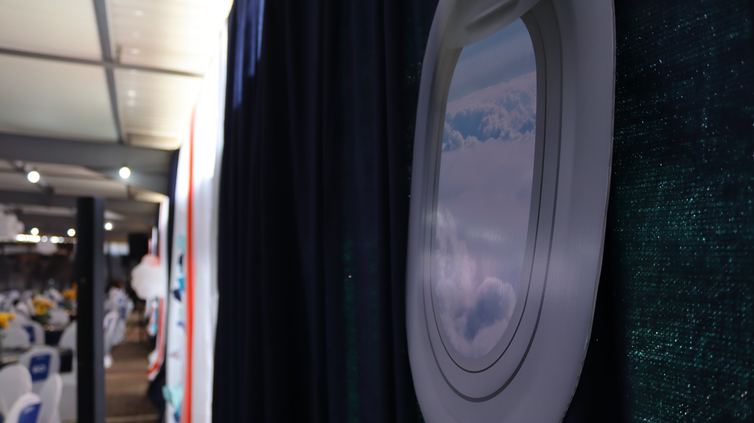 An airplane window showing a view of clouds and sky.